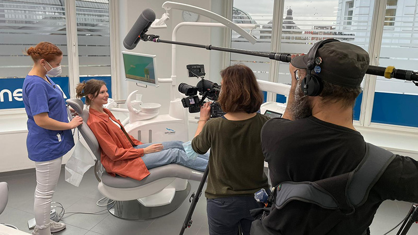 Filmteam dreht in einer Zahnarztpraxis, w&auml;hrend eine Patientin im Behandlungsstuhl sitzt und von einer zahnmedizinischen Fachangestellten betreut wird